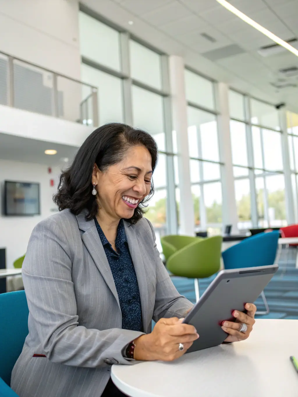 A school administrator smiling while reviewing a simplified IT management dashboard on a tablet, showcasing the ease of use and efficiency of Nozhian's services.